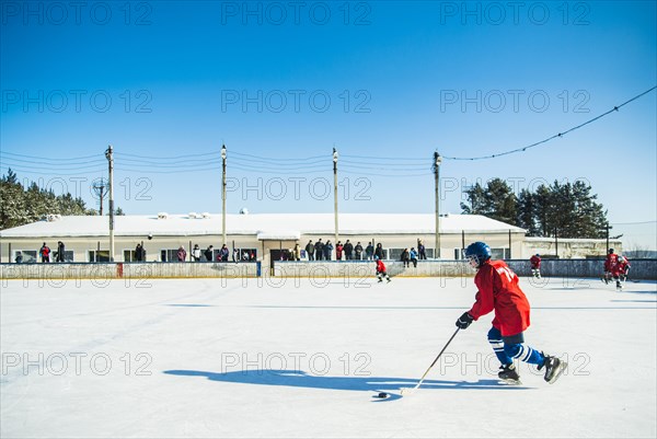 Caucasian boys playing ice hockey outdoors