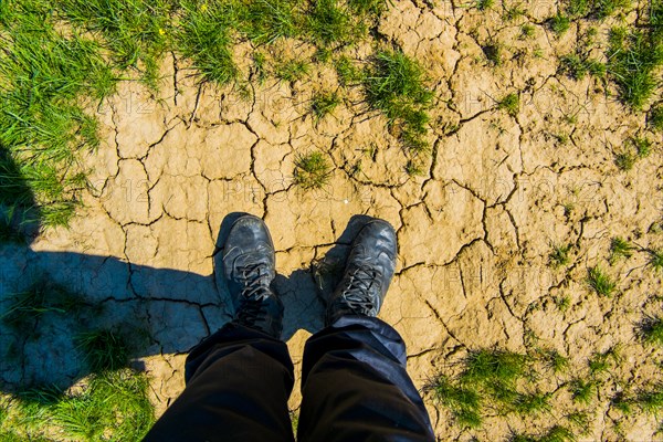 Person wearing boots on dry cracked ground