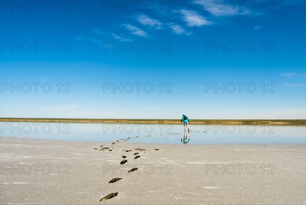 Footprints of woman wearing backpack on beach