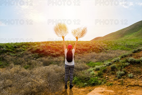Woman standing in rolling landscape holding branches