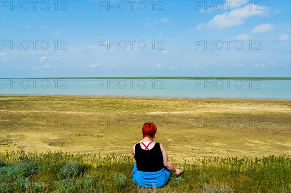 Woman sitting in grass near beach