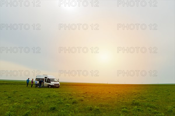 Caucasian friends standing in field near van