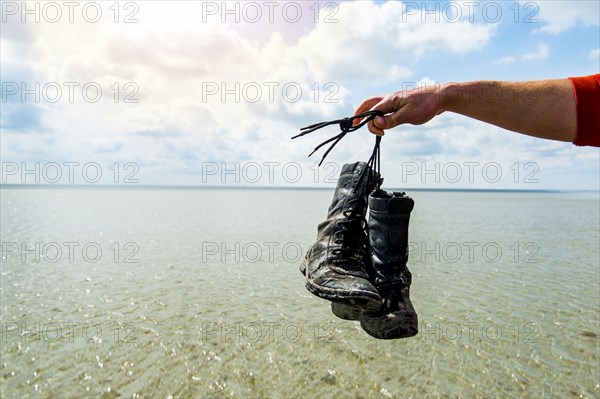 Arm holding boots over water