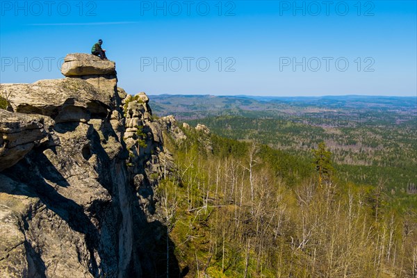 Caucasian man sitting on mountain rock admiring scenic view