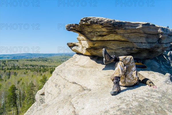 Caucasian man laying on mountain rock under blue sky