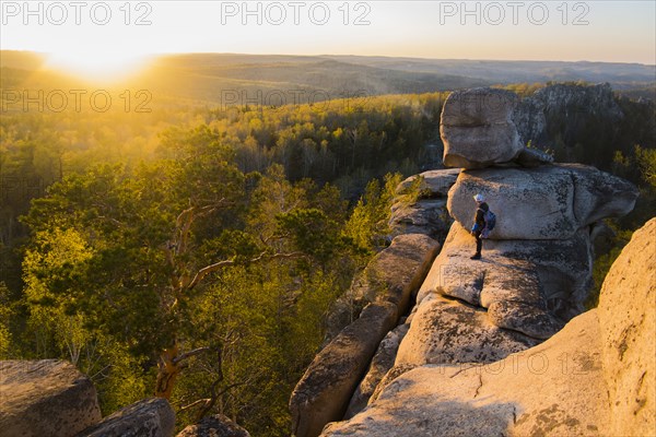 Caucasian man standing on mountain rock admiring sunset