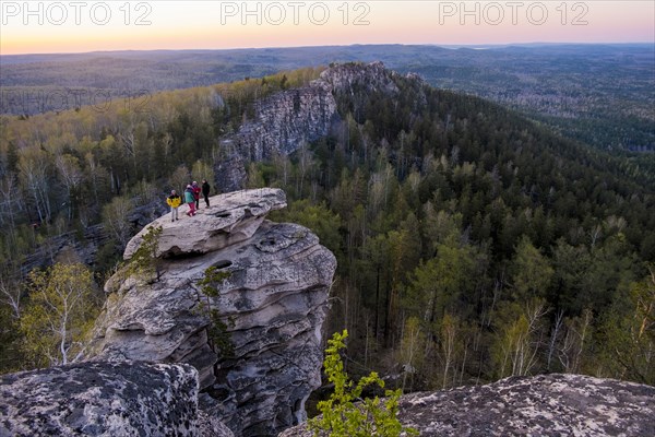 Caucasian friends standing on mountain rock admiring scenic view