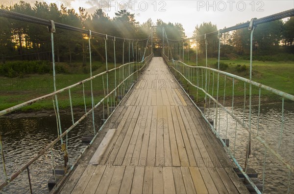 Sunbeams on wooden footbridge over river