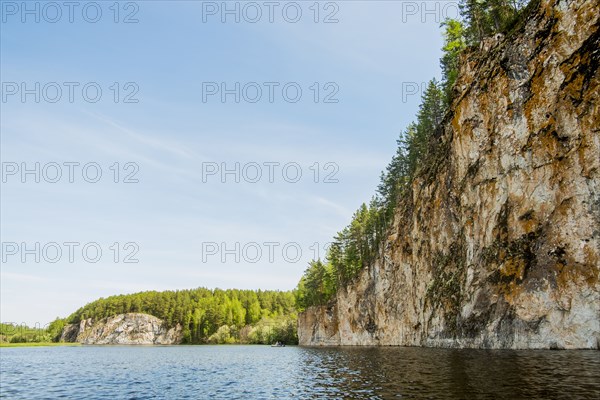 Distant inflatable raft on river near cliff