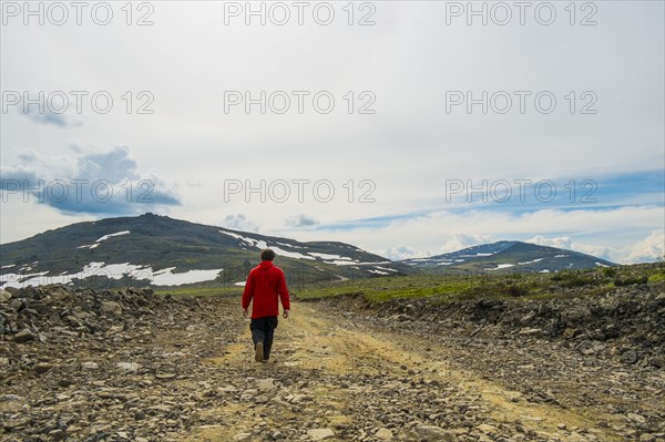 Man walking on mountain path in winter