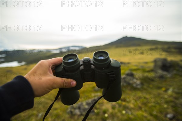 Hand of man holding binoculars outdoors