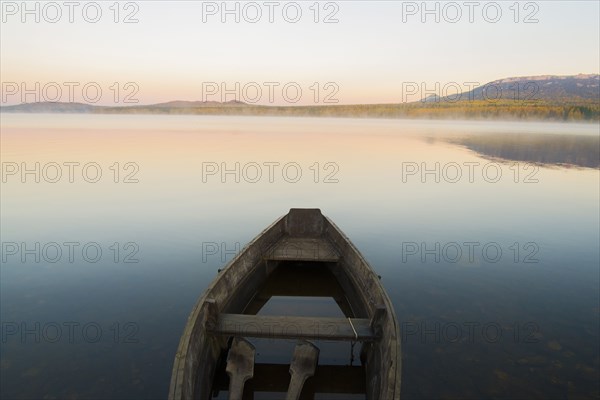 Empty rowboat on lake at sunset