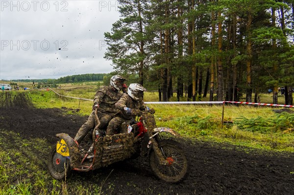 Caucasian racers on motorcycle with side car spraying dirt