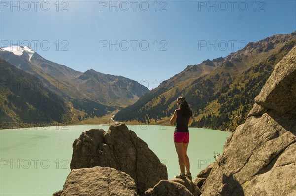 Caucasian woman standing on rocks near mountain lake