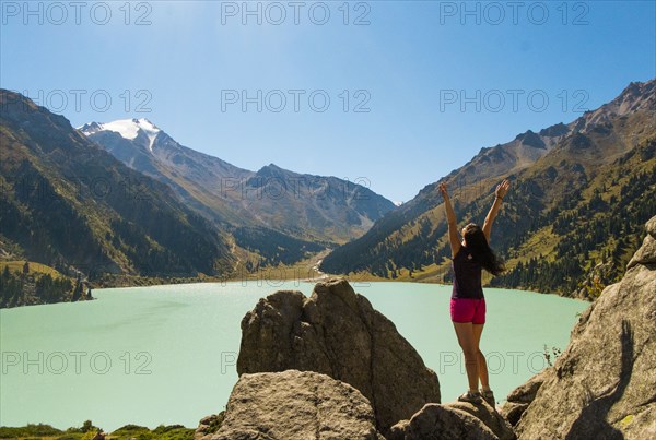 Caucasian woman celebrating on rocks near mountain lake