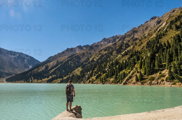 Caucasian man standing on rock near mountain lake