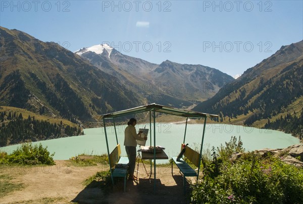 Caucasian woman painting mountain landscape