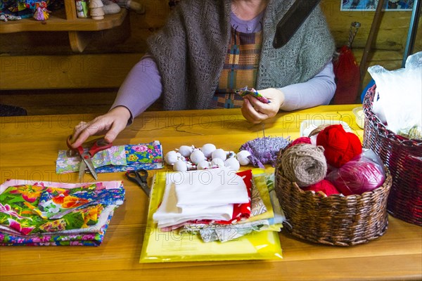 Woman sewing fabric reaching for scissors at table