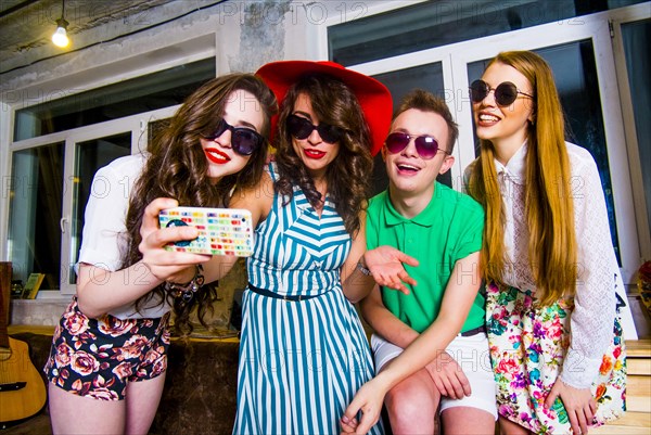 Fashionable Caucasian friends posing for cell phone selfie