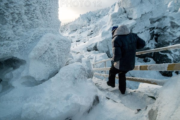 Caucasian man descending snowy staircase near rocks