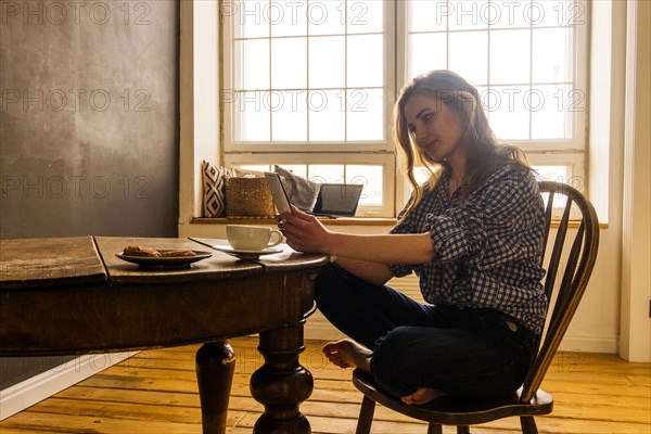 Caucasian woman reading digital tablet at table