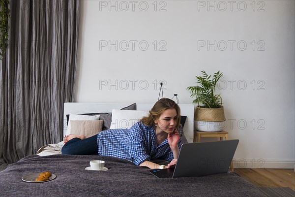 Caucasian woman laying on bed using laptop