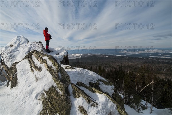 Caucasian man standing in snow admiring scenic view of forest
