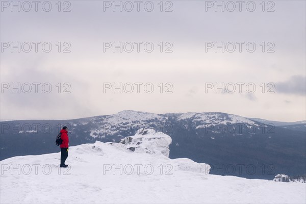 Caucasian man standing on remote mountain in winter