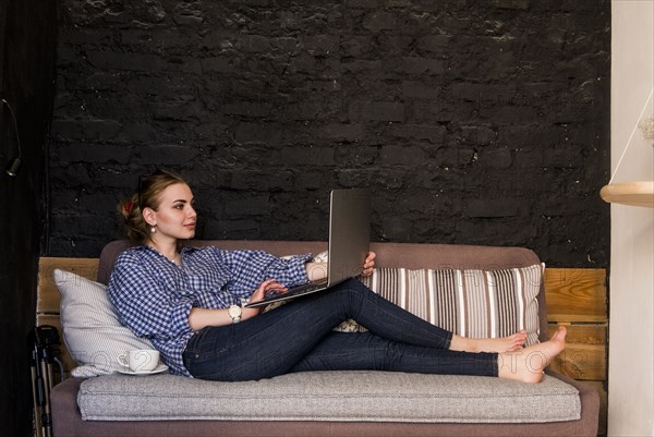 Caucasian woman sitting on sofa using laptop