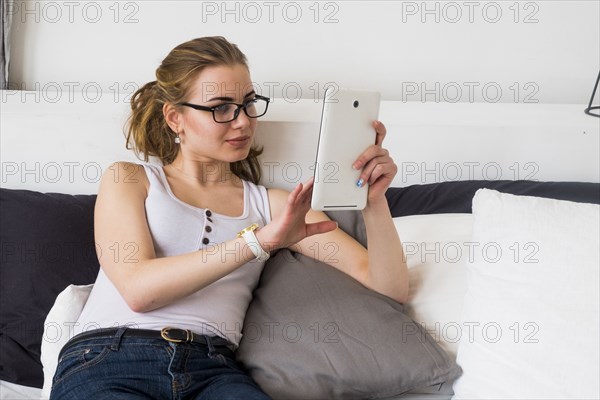 Caucasian woman sitting on bed using digital tablet