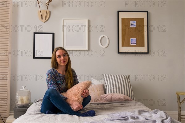 Portrait of smiling Caucasian woman sitting on bed