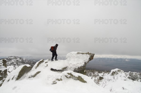 Distant Caucasian man standing on mountain in winter