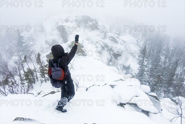 Caucasian hiker waving on snow covered mountain