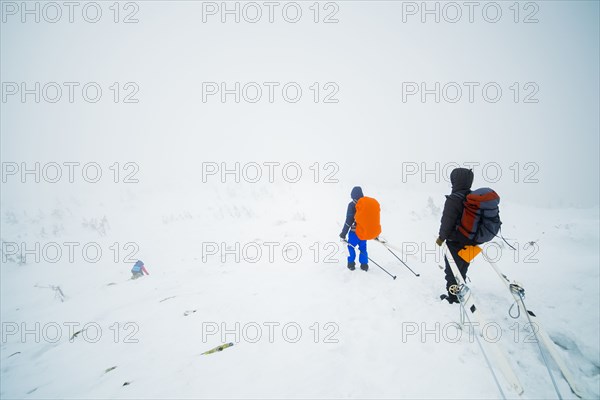 Caucasian hikers carrying skis on mountain