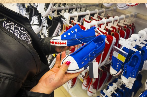 Hands of Caucasian woman holding sneakers in store