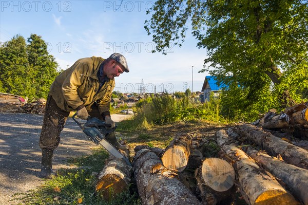 Caucasian man cutting logs with chainsaw