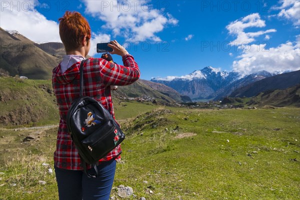 Caucasian woman photographing mountain with cell phone