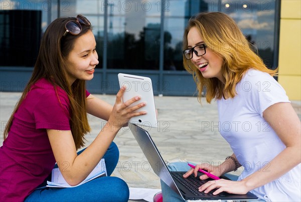 Caucasian women using laptop and digital tablet outdoors