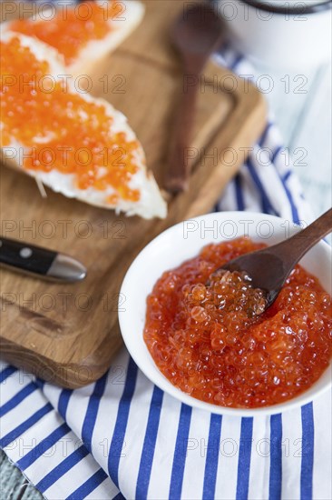 Bowl of caviar near bread on cutting board