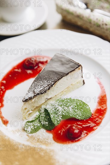 Cheesecake slice on plate with powdered sugar and berry sauce