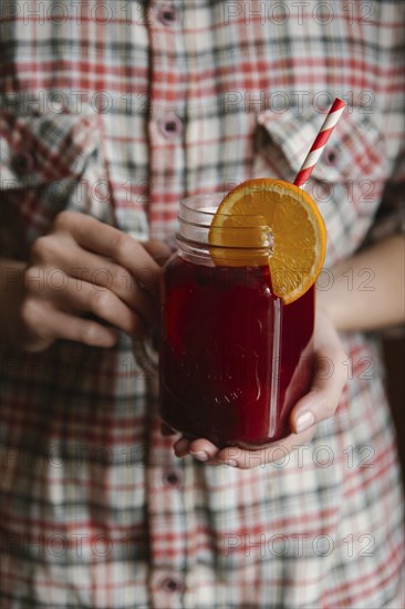 Woman holding glass of fruit tea with straw