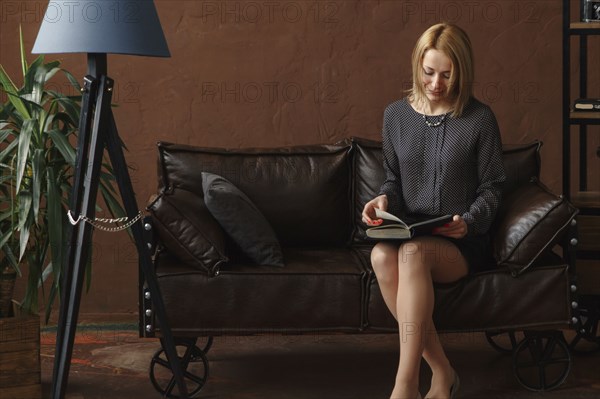 Middle Eastern woman sitting on sofa reading book