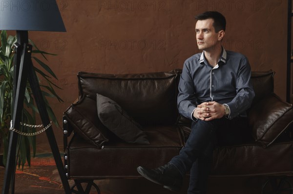 Pensive Middle Eastern man sitting on sofa