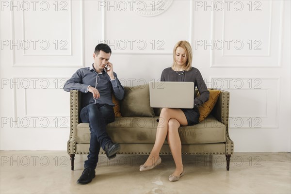Middle Eastern couple sitting on sofa using technology