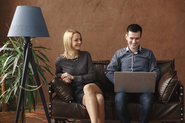 Middle Eastern couple sitting on sofa using laptop