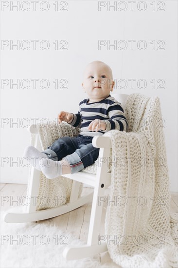 Curious Caucasian baby boy sitting in chair