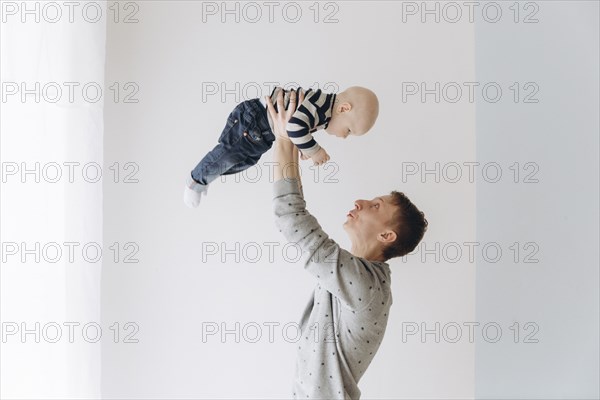 Caucasian father lifting baby son