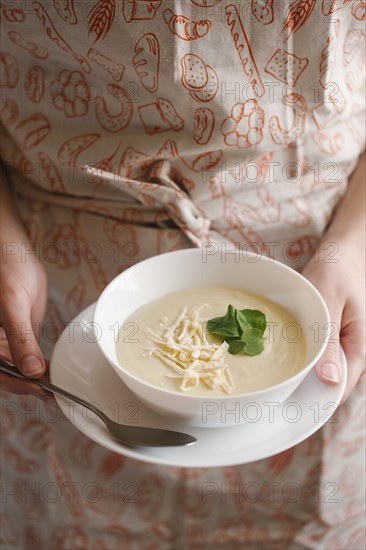 Woman holding bowl of cheese soup