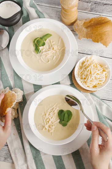 Hands of woman eating bowl of cheese soup