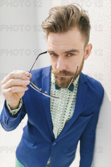 Portrait of stylish Middle Eastern man with beard holding eyeglasses